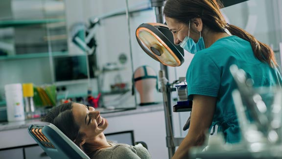 Young smiling woman talking to her dentist at dentist's office.