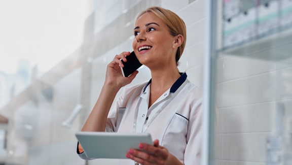An African American woman is sitting on the bed in the bedroom communicating with the doctor online while holding a bottle of medicine in her hand